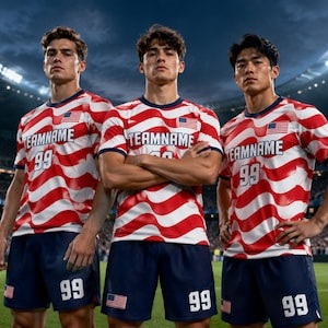 May include: Three soccer players wearing red and white striped jerseys with the American flag on the chest. The jerseys have the text "TEAMNAME" and the number "99". They are also wearing navy blue shorts with the number "99" and the American flag.