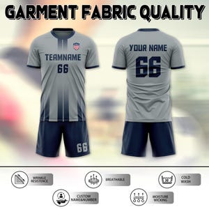 May include: A gray soccer uniform set with navy blue accents, featuring the text "TEAMNAME" and the number "66" on the front and back. The uniform includes a jersey and shorts, with the text "GARMENT FABRIC QUALITY" at the top.