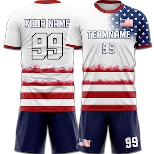 May include: White soccer jersey with red and white stripes, blue shorts. The jersey features the text "YOUR NAME" and "TEAMNAME", with the number "99". The right sleeve has a blue background with white stars and a small American flag.