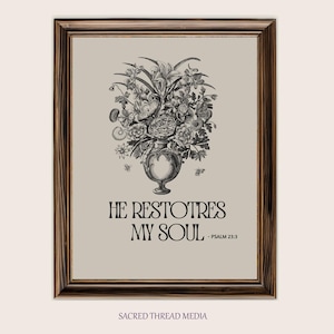May include: Framed art print featuring a black and white floral bouquet in a decorative vase. The artwork includes the text "HE RESTORES MY SOUL - PSALM 23:3" in a serif font. The frame is a dark brown wood.