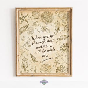 Peut inclure: Impression encadrée de style vintage avec des coquillages, des étoiles de mer et des hippocampes. Le texte dit : « Lorsque tu traverses les eaux profondes, je serai avec toi. Esaïe 43:2. » Le cadre est de couleur marron clair.