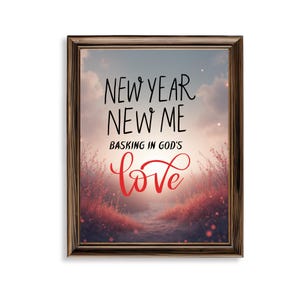 May include: Framed art print with the text "NEW YEAR NEW ME BASKING IN GOD'S love" in black and red script. The artwork features a scenic background with a path leading towards a bright light, framed in a brown wooden frame.