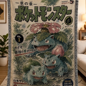 May include: A woven throw blanket featuring a vintage manga cover design with Bulbasaur, Ivysaur, and Venusaur. The cream-colored fabric displays Japanese text, the title Pocket Monsters, and a grass-type symbol. It has a fringed edge and a textured finish.