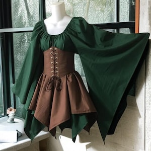 Könnte beinhalten: Ein mittelalterliches Kleid in Grün und Braun mit Korsett-Oberteil und ausgestellten Ärmeln. Das Oberteil ist braun mit Schnürung vorne, und der Rock ist mit grünem und braunem Stoff überlagert. Das Kleid wird auf einer Schaufensterpuppe präsentiert.