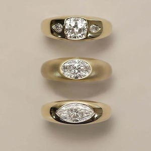 Op de afbeelding: Drie gouden ringen met diamanten als middenstenen. De bovenste ring heeft een vierkant geslepen diamant met twee kleinere peervormige diamanten. De middelste ring heeft een ovaal geslepen diamant. De onderste ring heeft een marquise-geslepen diamant.