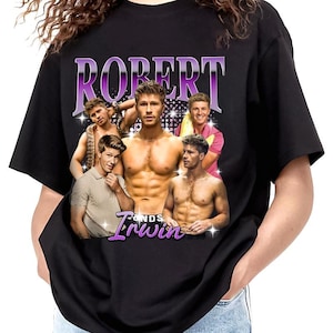 May include: Black t-shirt featuring a graphic of five men with the text "ROBERT" in a purple, retro font above the image and "Irwin" in a similar font below. The men are in various poses, some shirtless.