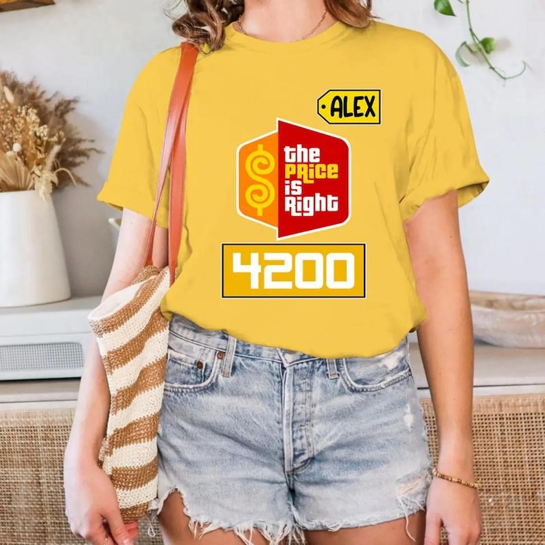 May include: A yellow t-shirt with the "The Price is Right" logo. The design includes the text "the Price is Right" in red and white, and the number "4200". The name "ALEX" is printed on a tag. The shirt is a casual wear item.