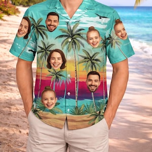 May include: Short-sleeved button-down shirt with a tropical beach scene and palm trees. The shirt features faces of people on the palm trees. The background shows a beach with a colorful sunset and ocean.