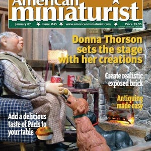 Peut inclure: La couverture du magazine "American Miniaturist" présente une scène miniature avec une figurine, deux chiens et une cheminée. Le texte comprend "Donna Thorson sets the stage with her creations" et "Add a delicious taste of Paris to your table."