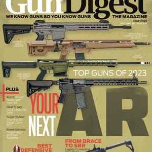 May include: The cover of Gun Digest magazine features several firearms, including rifles and a pistol, with the text "Top Guns of 2023." The magazine's title and issue information are also visible, along with articles about AR triggers and defensive loads.