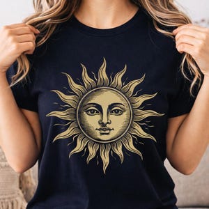 Woman wearing a black celestial sun graphic t-shirt with vintage boho design, styled as a mystical unisex astrology shirt for everyday casual wear