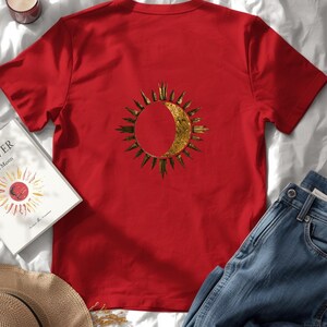 Flatlay of a organic cotton red tee with a big astrology sun and moon statement print on the back. Celestial zodiac design.