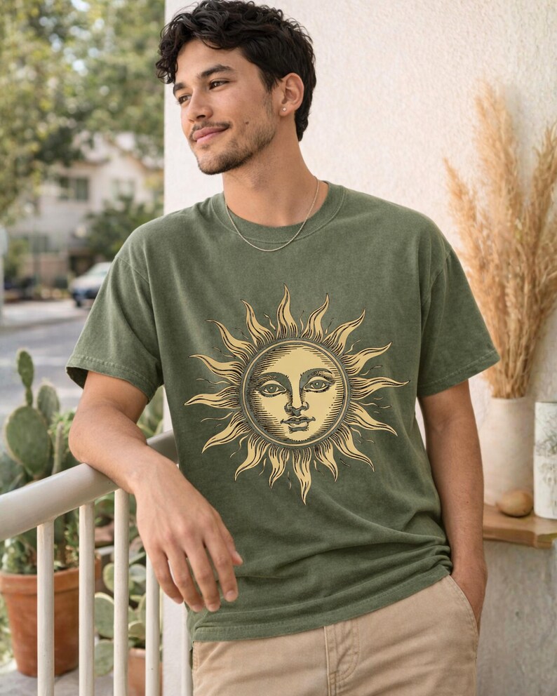 Man wearing an olive green / moss celestial graphic tee with vintage sun design, styled as a unisex boho astrology shirt for relaxed everyday wear