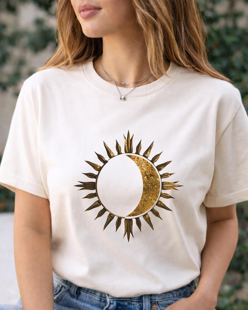 White organic cotton T-shirt with gold sun and moon cosmic design worn by a man outdoors. Minimalist astrology graphic.