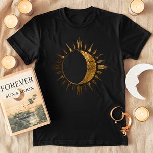 Flatlay Sun and Moon minimalist celestial print on a black organic cotton T-shirt. Detailed view of the front graphic.