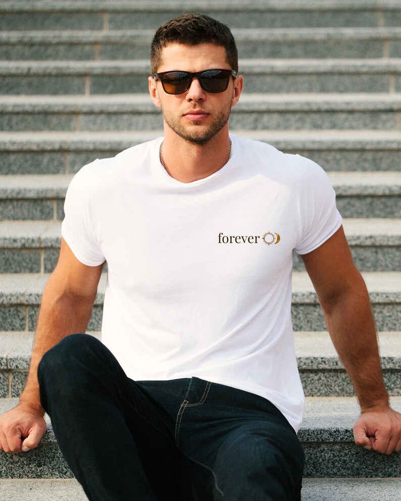 A men wearing a white shirt with a small astrology chest print with FOREVER and sun and moon. Boho whitchy minimalist gift for him.