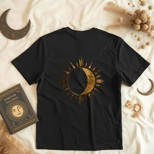 Flatlay of a black organic cotton shirt with a big astrology sun and moon statement print on the back. Celestial minimalist design.