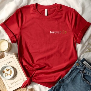 Flatlay of a organic cotton red shirt with a small astrology chest print with FOREVER and sun and moon. Celestial astrology whitchy minimalist design.