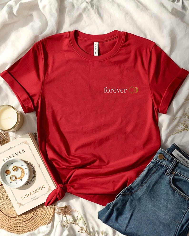 Flatlay of a organic cotton red shirt with a small astrology chest print with FOREVER and sun and moon. Celestial astrology whitchy minimalist design.