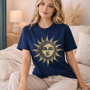 Woman sitting in a navy blue sun moon graphic tee with vintage celestial design, styled as a boho astrology shirt with a soft mystical aesthetic