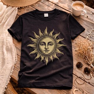 Black unisex graphic t-shirt with vintage sun face design laid flat, a celestial boho shirt for astrology lovers and spiritual gift ideas
