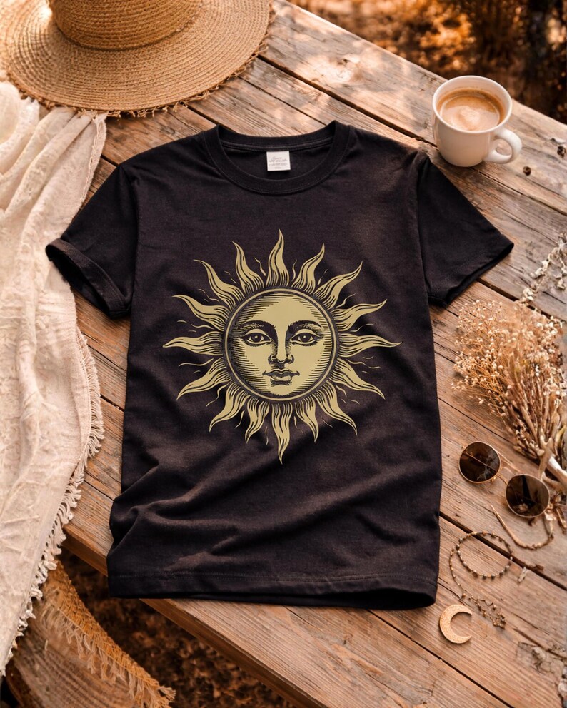 Black unisex graphic t-shirt with vintage sun face design laid flat, a celestial boho shirt for astrology lovers and spiritual gift ideas