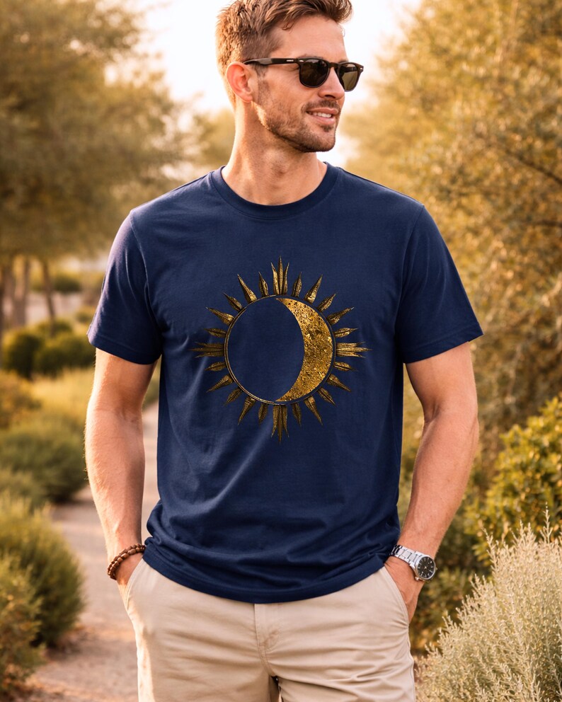 Navy blue organic cotton T-shirt with gold sun and moon cosmic design worn by a man outdoors. Minimalist astrology graphic.