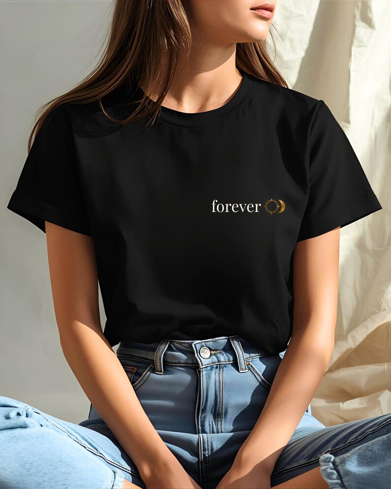 Woman wearing an black t-shirt with small "forever" sun and moon chest print. Celestial boho design, gift for her and him.
