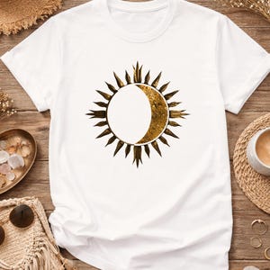Flatlay of a white tee with Sun and Moon minimalist celestial print. Detailed view of the front astrology graphic.