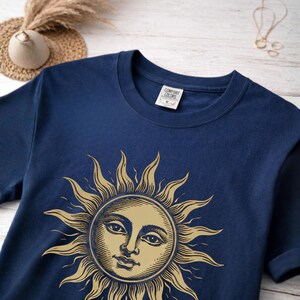 Navy unisex graphic t-shirt with vintage sun face design laid flat, a celestial boho shirt for astrology lovers and spiritual gift ideas, material close-up