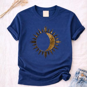 Flatlay of a blue navy tee with Sun and Moon minimalist celestial print. Detailed view of the front astrology graphic.