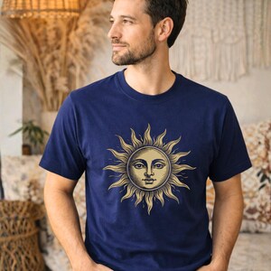 Man wearing a navy blue celestial sun graphic t-shirt with vintage boho style, a unisex astrology shirt with mystical spiritual aesthetic