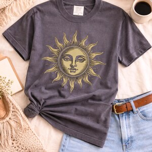 Grey comfort colors unisex t-shirt with vintage sun face design laid flat, a celestial boho shirt for astrology lovers and spiritual gift ideas