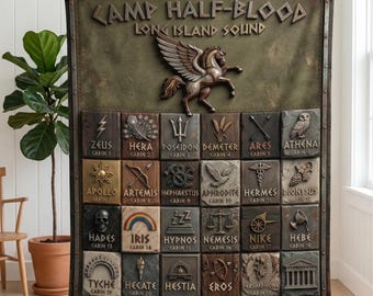 Op de afbeelding: Een decoratieve deken met een gedetailleerd ontwerp met de tekst "CAMP HALF-BLOOD LONG ISLAND SOUND" en verschillende Griekse godensymbolen. Een Pegasus-figuur staat bovenaan. De deken heeft een vintage uitstraling.