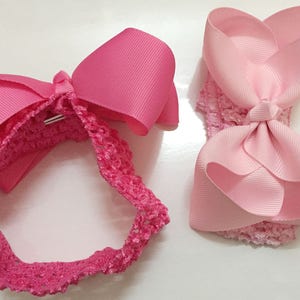 May include: Two pink hair bows with a crocheted headband. One bow is a simple bow and the other is a headband with a bow.