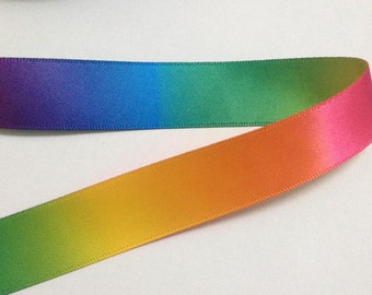 Puede incluir: Una cinta de satén degradada arcoíris con un degradado de morado, azul, verde, amarillo, naranja y rosa.