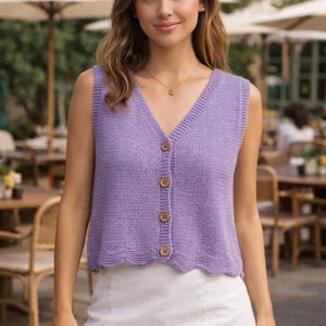 May include: A sleeveless, lavender-colored knit vest with a V-neck and wooden buttons. The vest has a scalloped hemline and is made of a soft, textured material. The garment is a stylish layering piece.