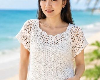 May include: A white short-sleeved crochet top featuring an intricate openwork pattern with a scalloped neckline and hem. The garment is constructed with a lightweight, airy stitch design, providing a textured appearance across the entire piece.
