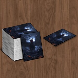 May include: A stack of rectangular cards featuring a dark fantasy illustration of a dragon with a full moon in the background. The dragon is black with red eyes and is surrounded by a dark, fiery landscape. Two cards are displayed separately.