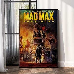 May include: A framed movie poster for "Mad Max: Fury Road" featuring Tom Hardy and Charlize Theron. The poster has a fiery, action-packed scene with vehicles and figures. The title is in bold yellow letters.