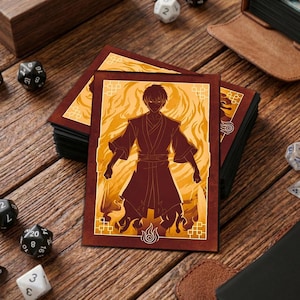 May include: A stack of trading card game sleeves featuring a character in a dark red robe with a yellow and orange flame design. The cards are on a wooden surface with dice and a leather card holder.