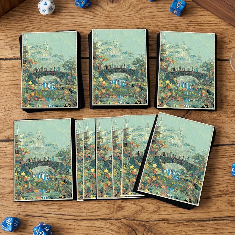 May include: Several card decks featuring a fantasy landscape with a bridge and figures, with the text "LORD RINGS". The decks have a black border and are arranged on a wooden surface. Dice are scattered around the decks.