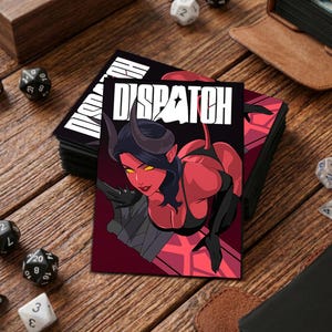 Könnte beinhalten: Ein Stapel schwarzer Kartenhüllen mit dem Wort "D'SPATCH" in Weiß. Die Kartenhülle zeigt eine rot-schwarze Illustration eines weiblichen Dämons mit Hörnern und gelben Augen. Würfel und ein ledergebundenes Notizbuch sind im Hintergrund.