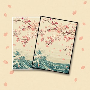 Op de afbeelding: Twee ingelijste kunstdrukken met een Japans geïnspireerd ontwerp. De kunstwerken tonen kersenbloesemtakken met roze bloemen en vallende bloemblaadjes boven gestileerde oceaangolven in blauw- en groentinten.