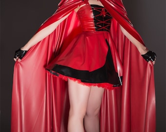 May include: A red hooded cape worn over a strapless red and black dress with a lace-up bodice and a flared skirt. The outfit includes black fingerless gloves and black high-heeled pumps, creating a cohesive ensemble with a glossy finish.