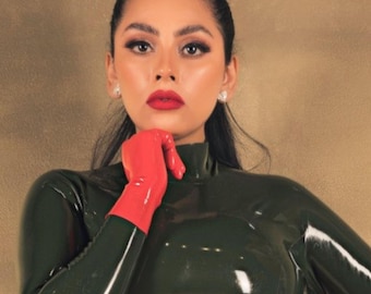 May include: A dark olive green long-sleeved crop top with a high neck, paired with a matching dark olive green military-style garrison cap featuring red side stripes and a single bright red glove on the right hand, creating a glossy finish.