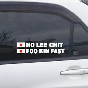 May include: White car window sticker with the text "HO LEE CHIT FOO KIN FAST" in white, with a red dot in a white square on the left of each line. The sticker is on a white car.