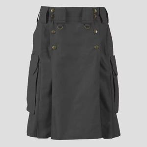 May include: A charcoal gray utility kilt featuring a flat front panel, side cargo pockets, and a waistband with belt loops. The garment includes metallic buttons and two D-rings positioned at the front for functional attachment points.