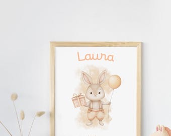 May include: A framed print featuring a watercolor illustration of a bunny holding a gift and a balloon. The print includes the name "Laura" and the date 20/11/2024, with measurements of 50 cm and 2.525 kg. The print is in a light wood frame.