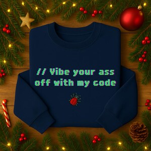 Könnte beinhalten: Ein marineblaues Sweatshirt mit dem Text "// Vibe your ass off with my code" in pixeligen grünen und blauen Buchstaben. Unter dem Text befindet sich eine rote Käfergrafik. Das Sweatshirt ist von Weihnachtsdekorationen umgeben.